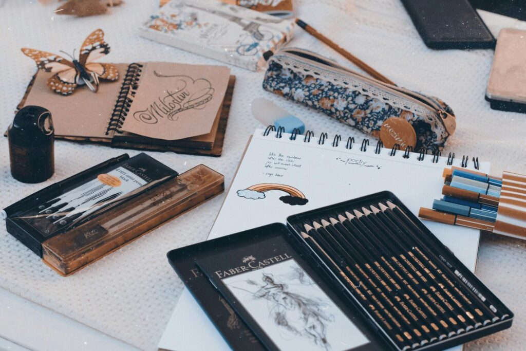 Art supplies including pencils, pens, and sketchbooks arranged on a table for creativity.